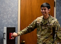 Airman demonstrates how to activate a fire pull switch.