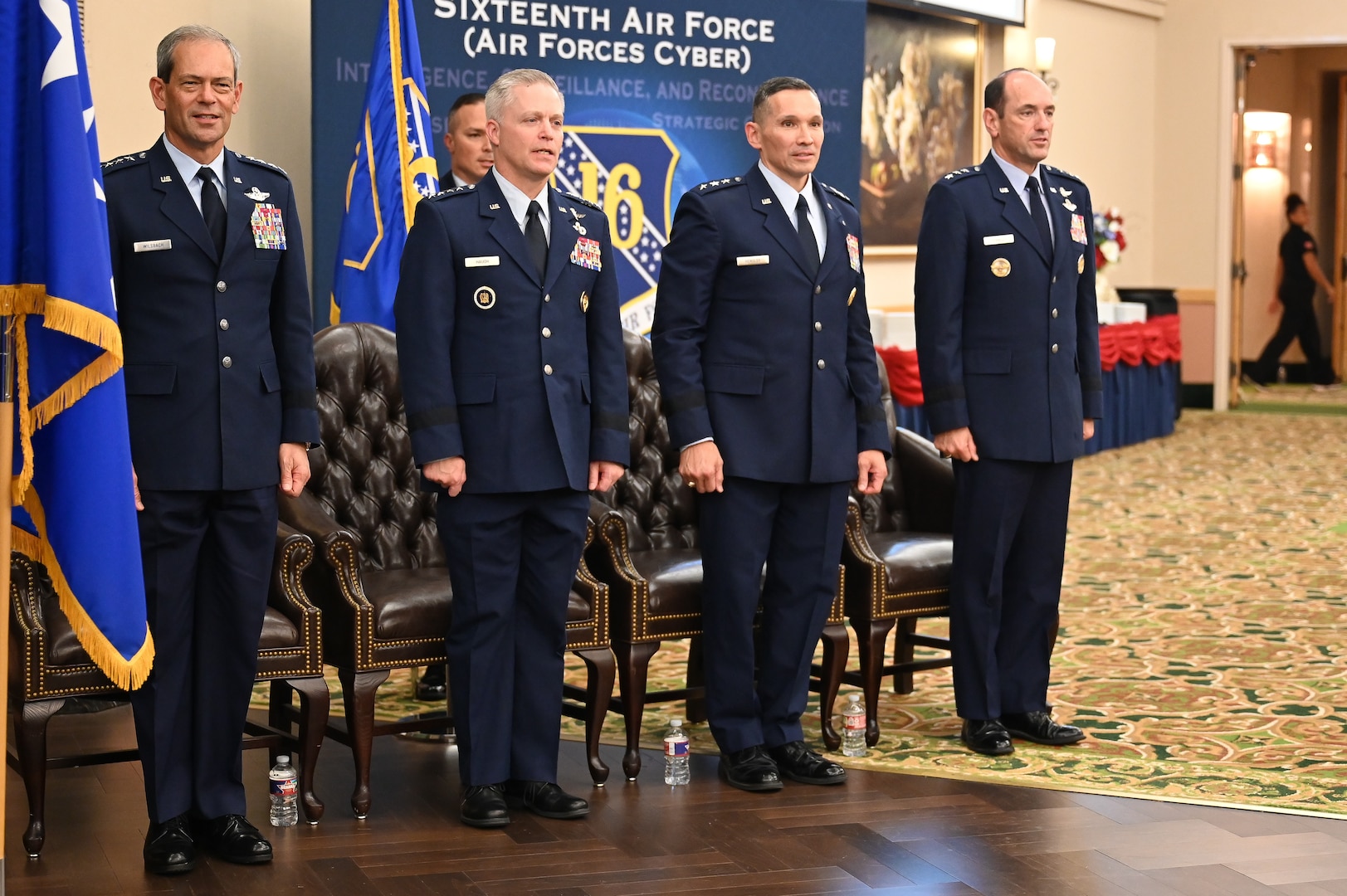 Air Force leadership stand at attention in front of audience