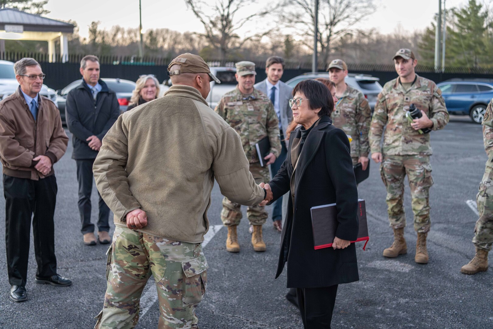 A woman in civilian attire shakes hands with a service member in uniform.