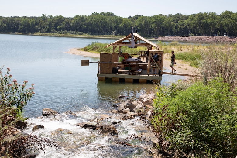 A raft named the Eagles Nest sits in a cove just of the Missouri River as Bald Eagle Boy Camp counselors and students apply finishing touches on their custom raft on Aug. 2, 2024. The U.S. Army Corps of Engineers, Omaha District, granted permission for the camp to use the cove for reassembly of their raft that was shipped from Pennsylvania. (U.S. Army photo by Josh Plueger)