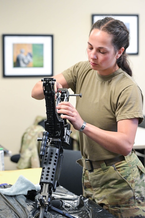 A female Airman, Michigan National Guard, disassembles an M-249 light machine gun.