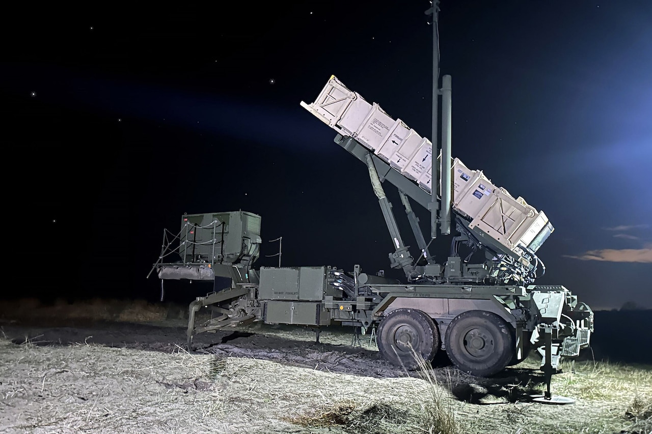 A trailer-mounted missile-launching system sits in a field at night.