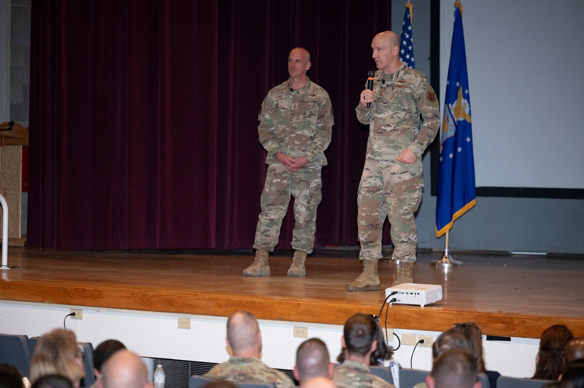 A man on stage talks to a crowd.