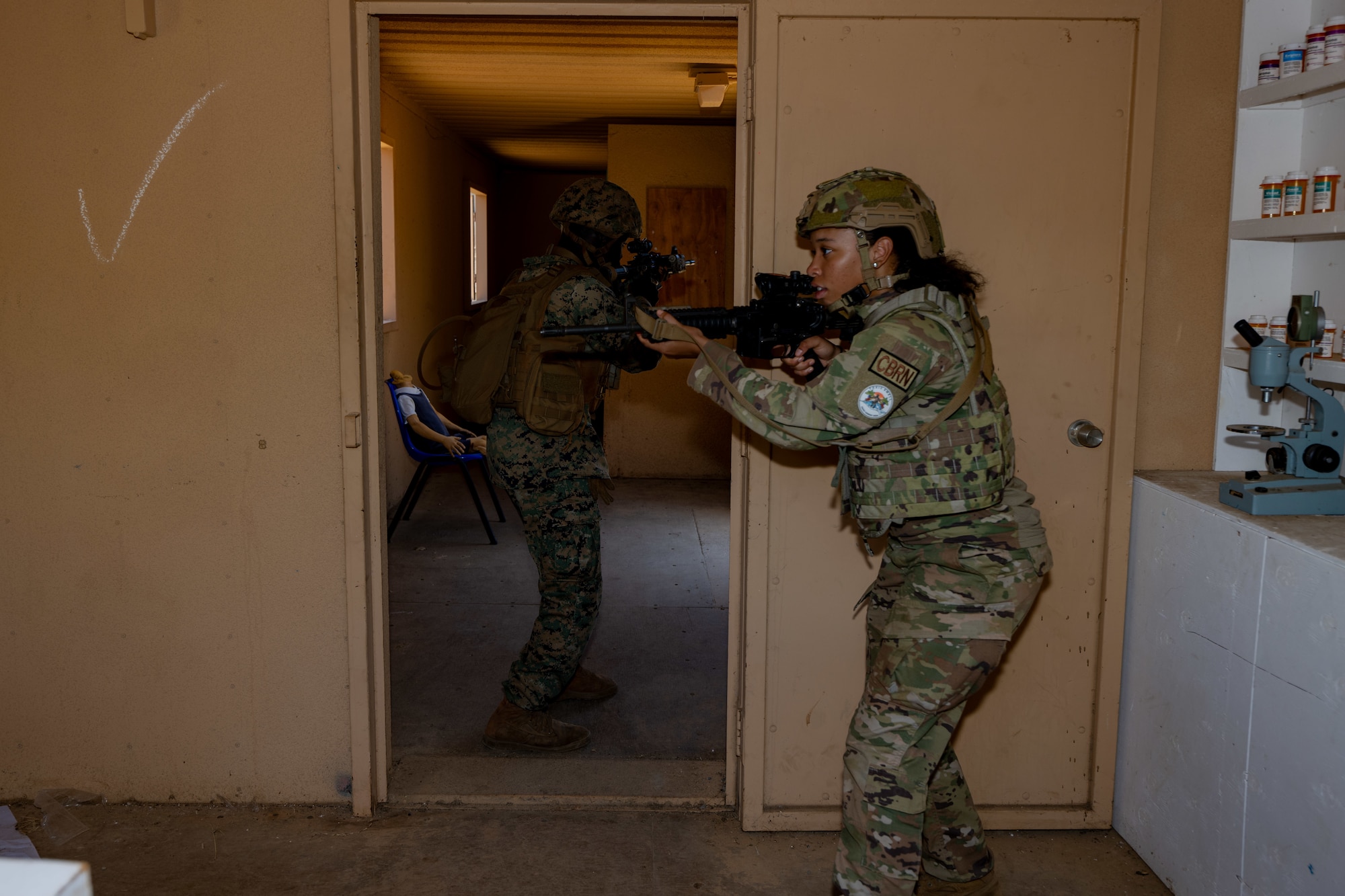 Airman stands guard at a door with a rifle.