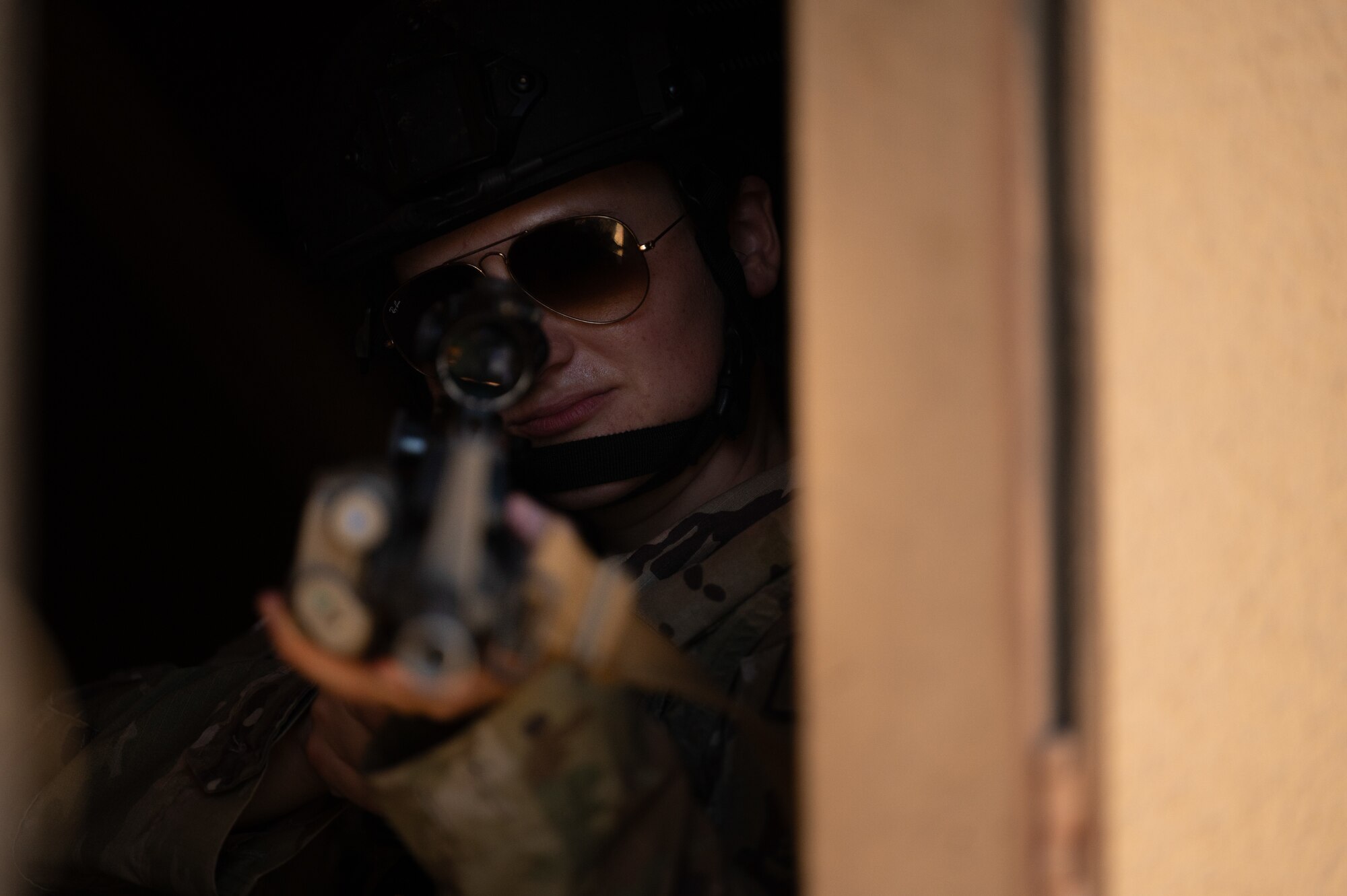 Airman stands guard at a window with a rifle.