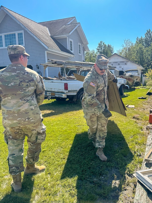 Alaska Army Guard Spc. Kyle Schramm, right, and Sgt. Heather Byrd, a military policeman with the 297th Military Police Detachment, and Spc. Jacob Miller, an infantryman with Alpha Company, 1st Battalion, 297th Infantry Regiment, assist Juneau residents with recovery and cleanup efforts Aug. 8, 2024, following recent flooding after the Mendenhall Glacier’s Suicide Basin released. The State Emergency Operations Center requested 40 members of the Alaska Organized Milita to assist with flood recovery efforts. Seven Guardsmen from Juneau began work Aug. 7, and an additional 33 Air and Army Guard volunteers from the Fairbanks and Anchorage will fly to Juneau in the coming days as part of JTF-J.