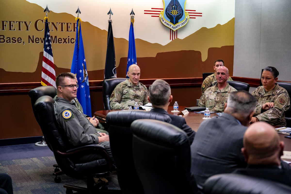 A bunch of people sitting around a desk in a briefing.