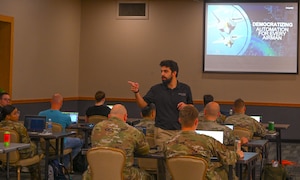 Kamlen Joshi, Invoke robotic processes automation (RPA) instructor, speaks to students about automating processes during the RPA course at Minot Air Force Base, North Dakota, August 6, 2024. The purpose of the roadshow was to have students think critically about what improvements can be made in their everyday processes using RPA.