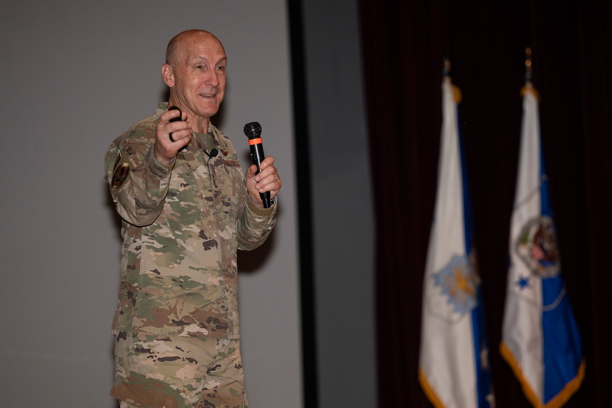 A man on stage talks to a crowd.