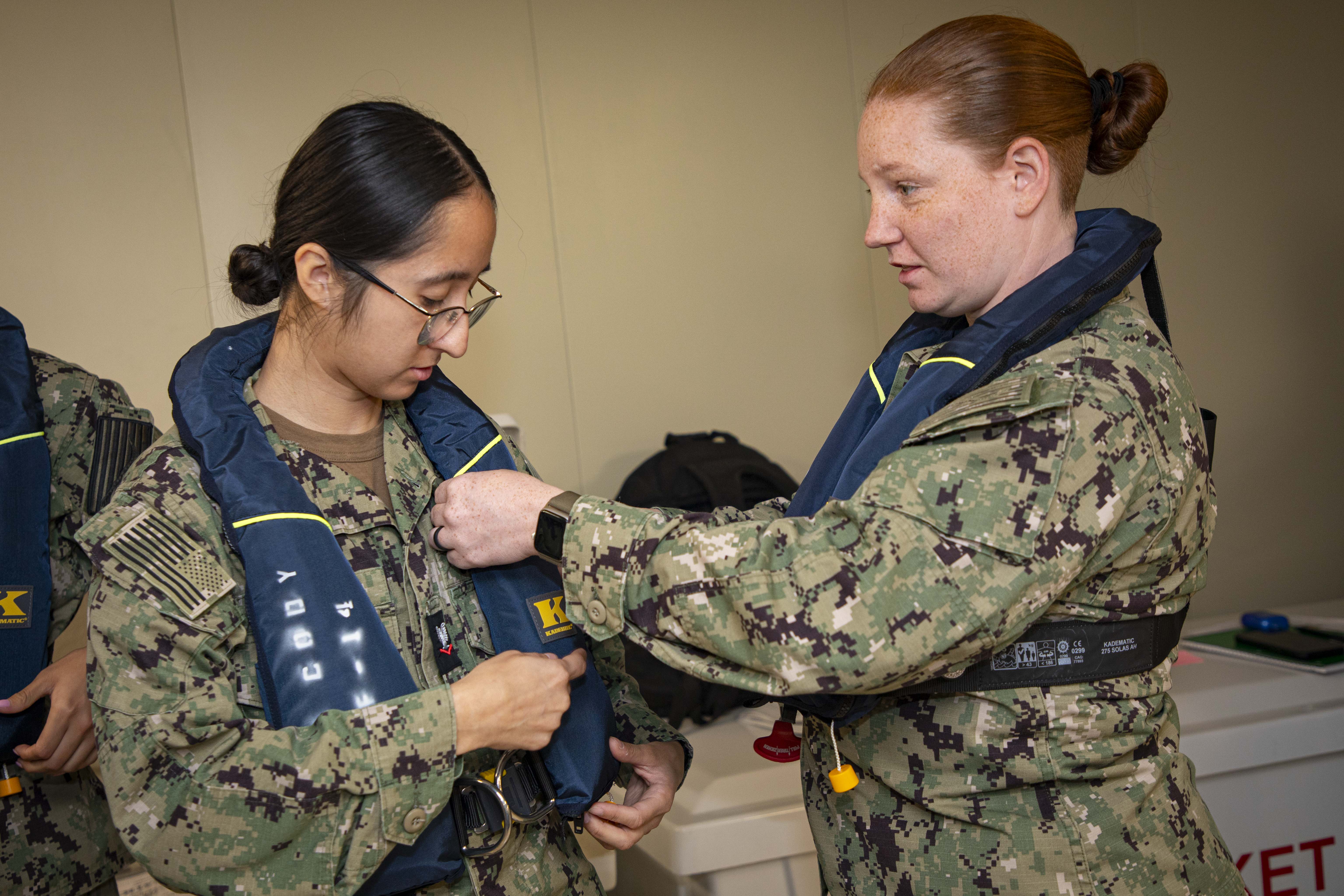 240723-N-KC192-1011 JOINT EXPEDITIONARY BASE LITTLE CREEK-FORT STORY, Va. (July 23, 2024) Hospital Corpsman 3rd Class Gennessy Palma, is assisted in donning a life jacket by Hospitalman Brandi Hopkins, assigned to Navy Medicine Readiness and Training Command (NMRTC) Jacksonville, during an evacuation drill onboard the transport ship USNS Cody (T-EPF 14), July 23, 2024. The U.S. Navy is embarking the first Expeditionary Medical Unit (EMU), a cutting-edge medical support system with support personnel from EMU-1, designed to provide Role 2 level healthcare services both afloat and ashore.  (U.S. Navy photo by Mass Communication Specialist 2nd Class Levi Decker)