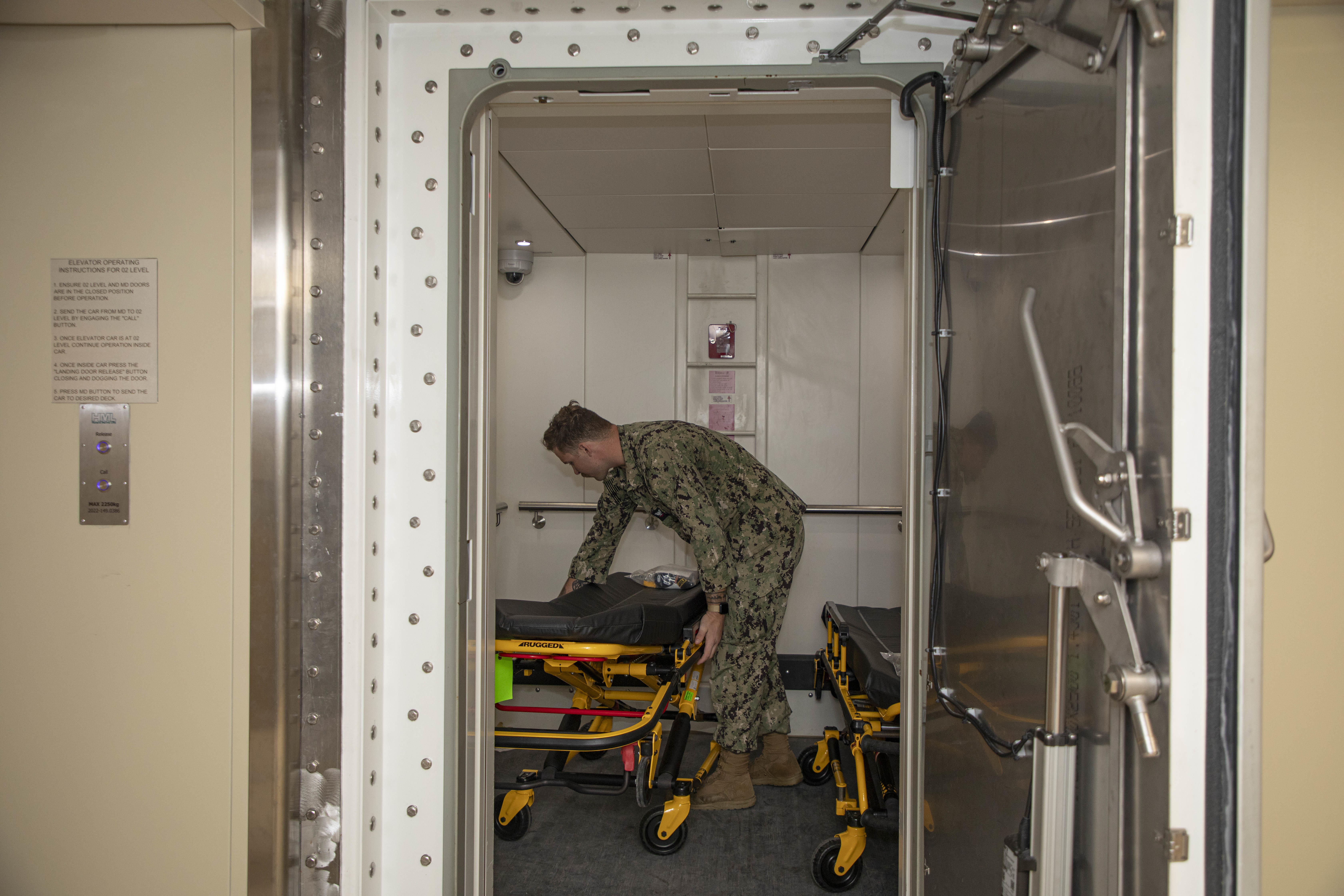 240722-N-KC192-1038 JOINT EXPEDITIONARY BASE LITTLE CREEK-FORT STORY, Va. (July 22, 2024) Hospital Corpsman 3rd Class Jacob ColeAllen, assigned to Navy Medicine Readiness and Training Command (NMRTC) Jacksonville, adjusts gurney in an elevator onboard the transport ship USNS Cody (T-EPF 14), July 22, 2024. The U.S. Navy is embarking the first Expeditionary Medical Unit (EMU), a cutting-edge medical support system with support personnel from EMU-1, designed to provide Role 2 level healthcare services both afloat and ashore.  (U.S. Navy photo by Mass Communication Specialist 2nd Class Levi Decker)