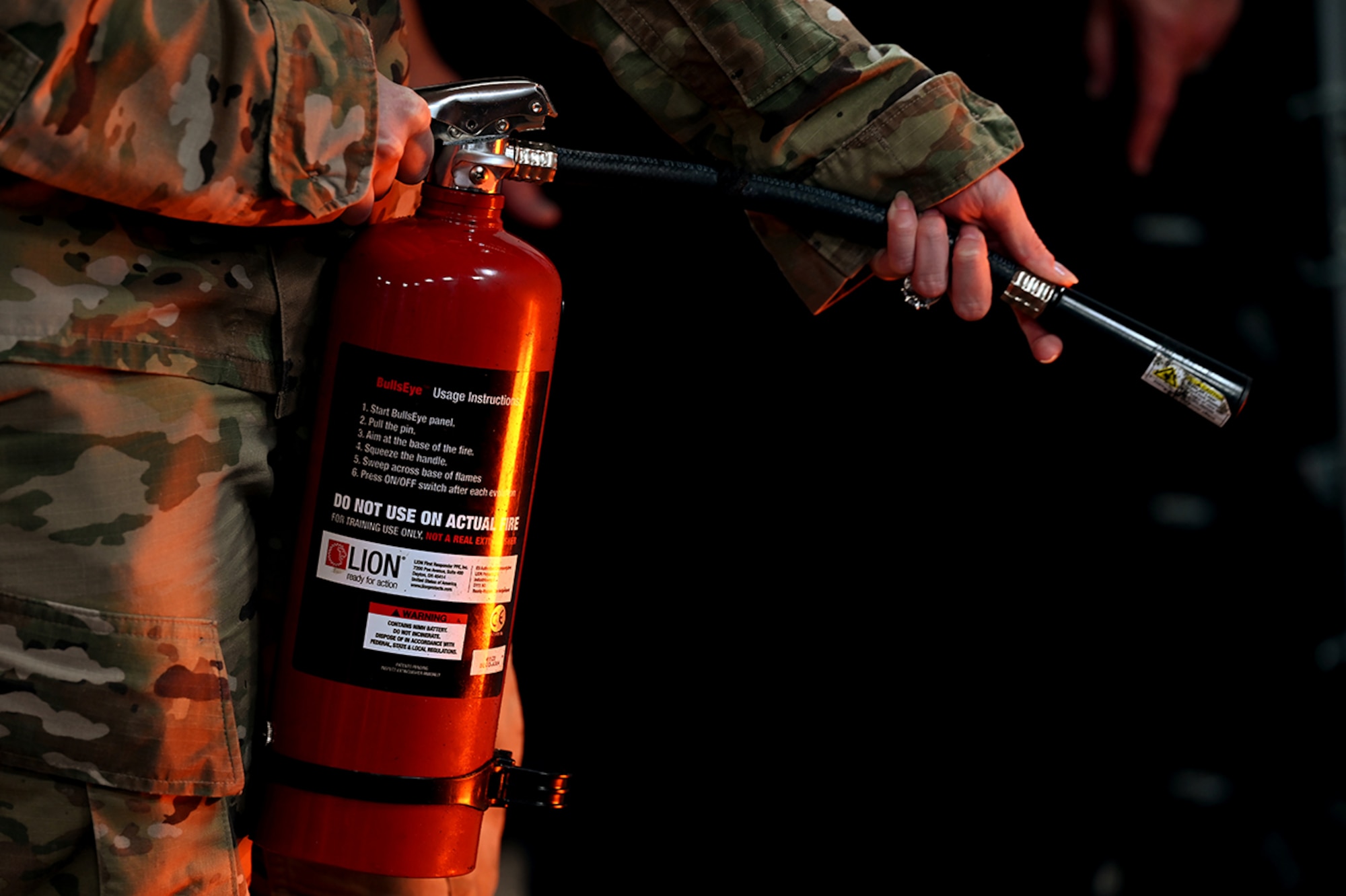 Airman holding a fire extinguisher pointing nozzle to the right.