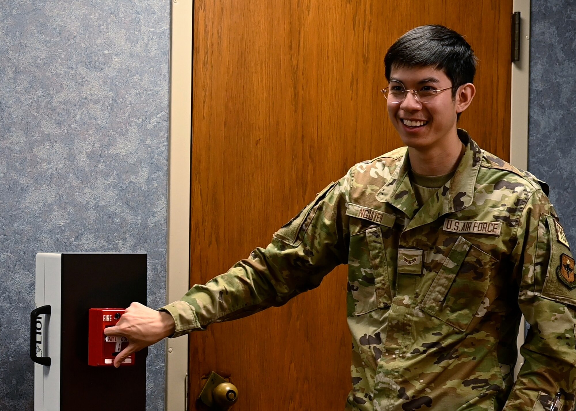 Airman demonstrates how to activate a fire pull switch.