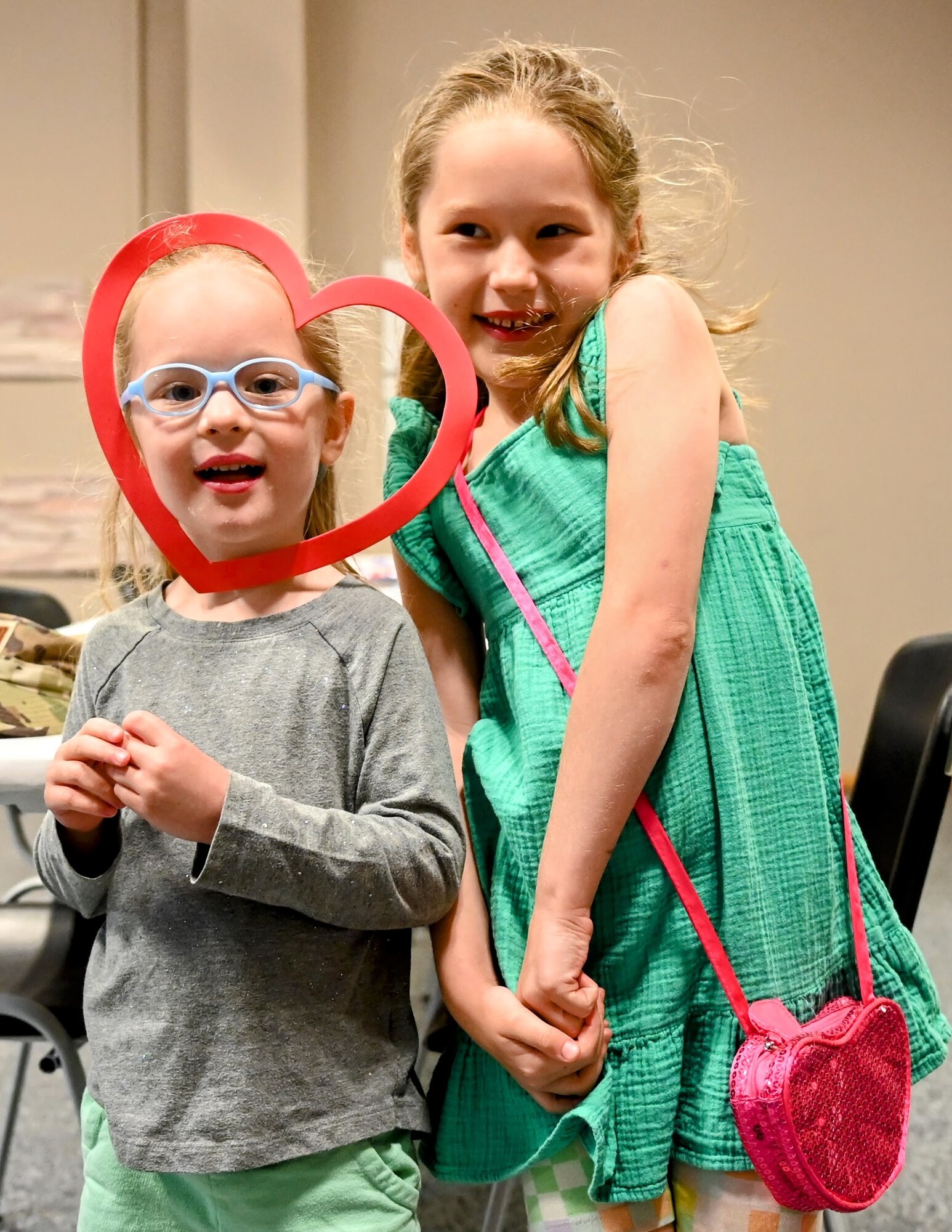 Two children smile at a camera at a craft event.