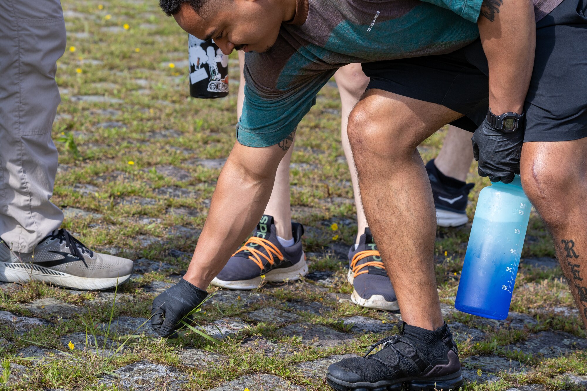 Student pulls weeds for an Airman Leadership School community service project