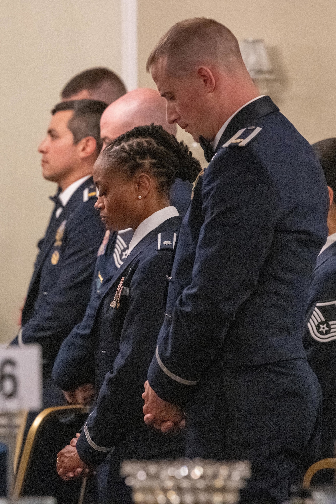 Attendees bow their heads during an Airman Leadership School graduation ceremony