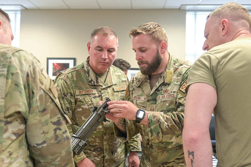 U.S. Air Force Tech. Sgt. Austin Brown, right, a defender assigned to the 127th Security Forces Squadron, Michigan National Guard, familiarizes Sr. Master Sgt. Adam Dittenber, left, an airframe, powerplant general section chief, 127th Aircraft Maintenance Squadron, with an M-249 light machine gun