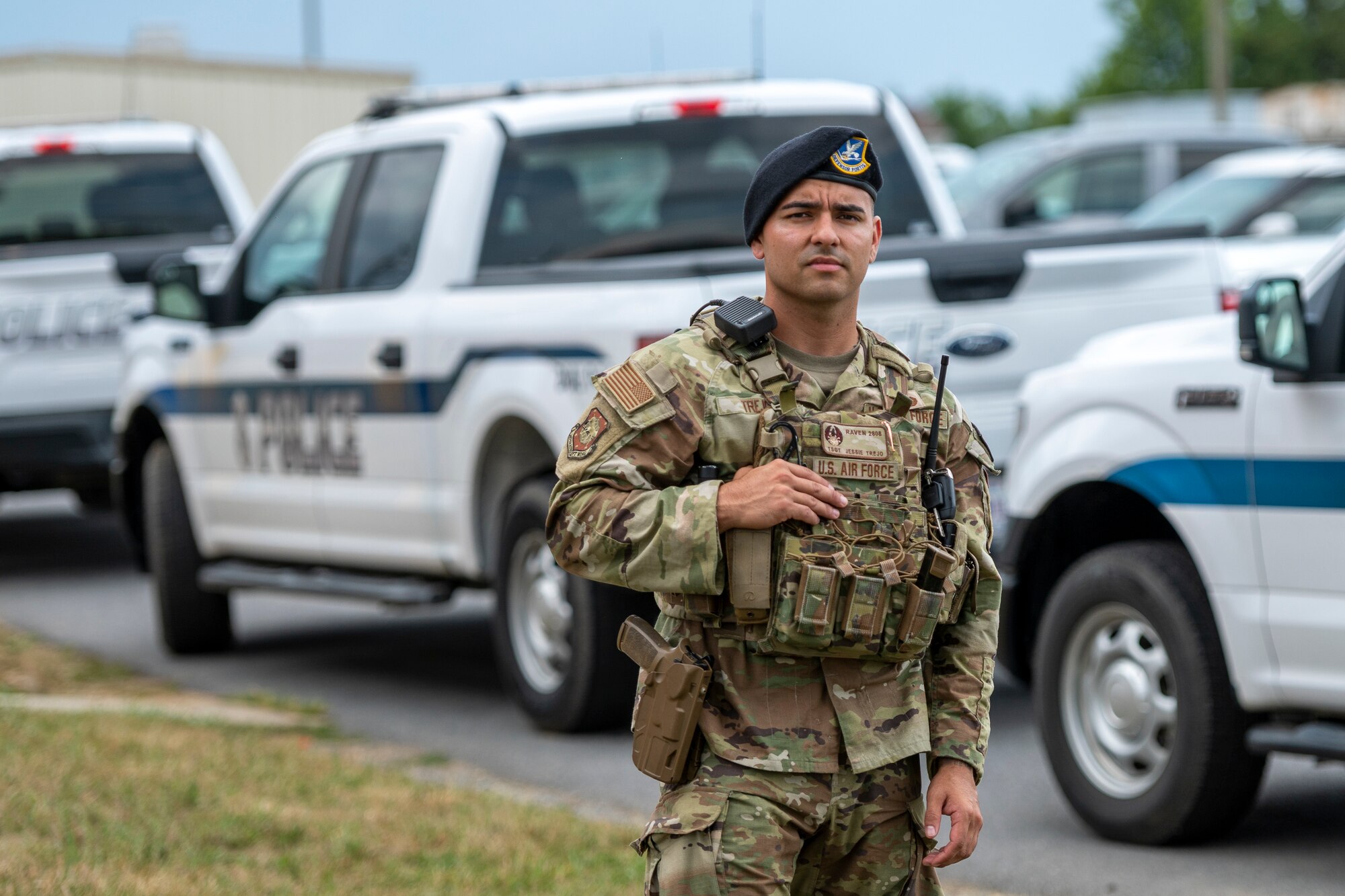 A man in uniform stands in front of police trucks