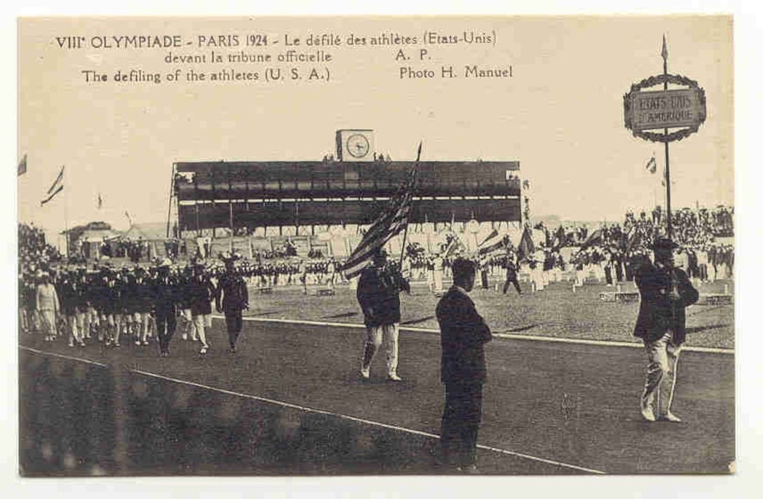 The athletes in white uniforms marching along the track in a stadium