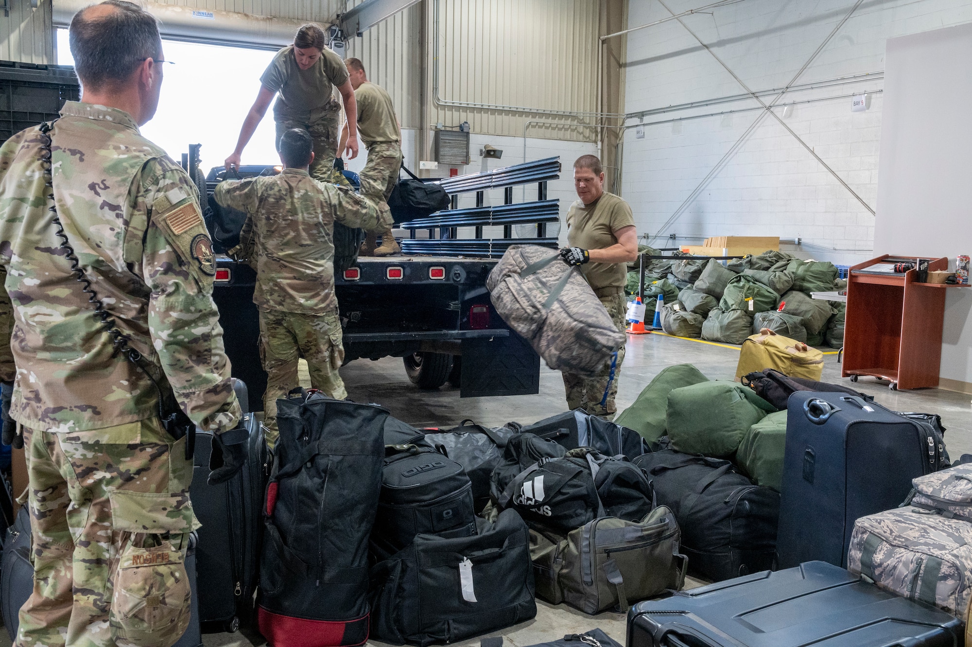 people in uniform move luggage out of the back of a truck