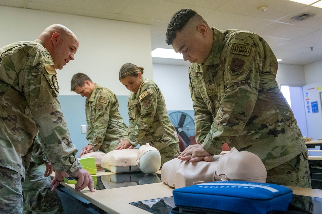 Men and women practice CPR techniques with medical dummies