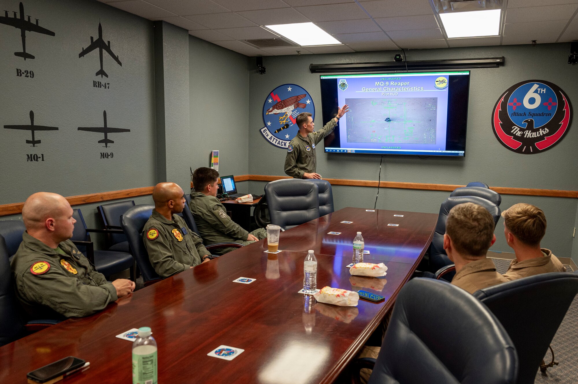 U.S. Air Force Capt. Christian Hogness, 6th Attack Squadron instructor pilot, center, briefs members of the 6th ATKS and Marines from the Marine Light Attack Helicopter Squadron 267 at Holloman Air Force Base, New Mexico, July 15, 2024. During their visit to the 6th ATKS, Marines from HMLA-267 and VMM-364, based at Marine Corps Air Station Camp Pendleton, Calif. witnessed the MQ-9 Reaper precision strike capabilities while demonstrating the capabilities of their respective aircraft. (U.S. Air Force photo by Senior Airman Isaiah Pedrazzini)