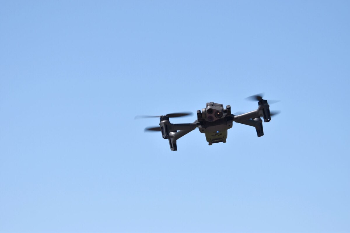 A small aircraft hovers against a blue sky.