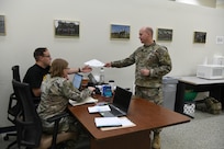 gt. Jimmy Pritchett, a human resources non-commissioned officer with 297th Regional Support Group, Alaska Army National Guard, hands documents to 1st Lt. Samuel Davis, a human resources officer with the 2nd Battalion, 300th Field Artillery, Wyoming Army National Guard, at the Soldier Readiness Processing site during Mobilization Exercise (MOBEX) III held at Camp Funston on Fort Riley, Kansas, Aug. 6, 2024.