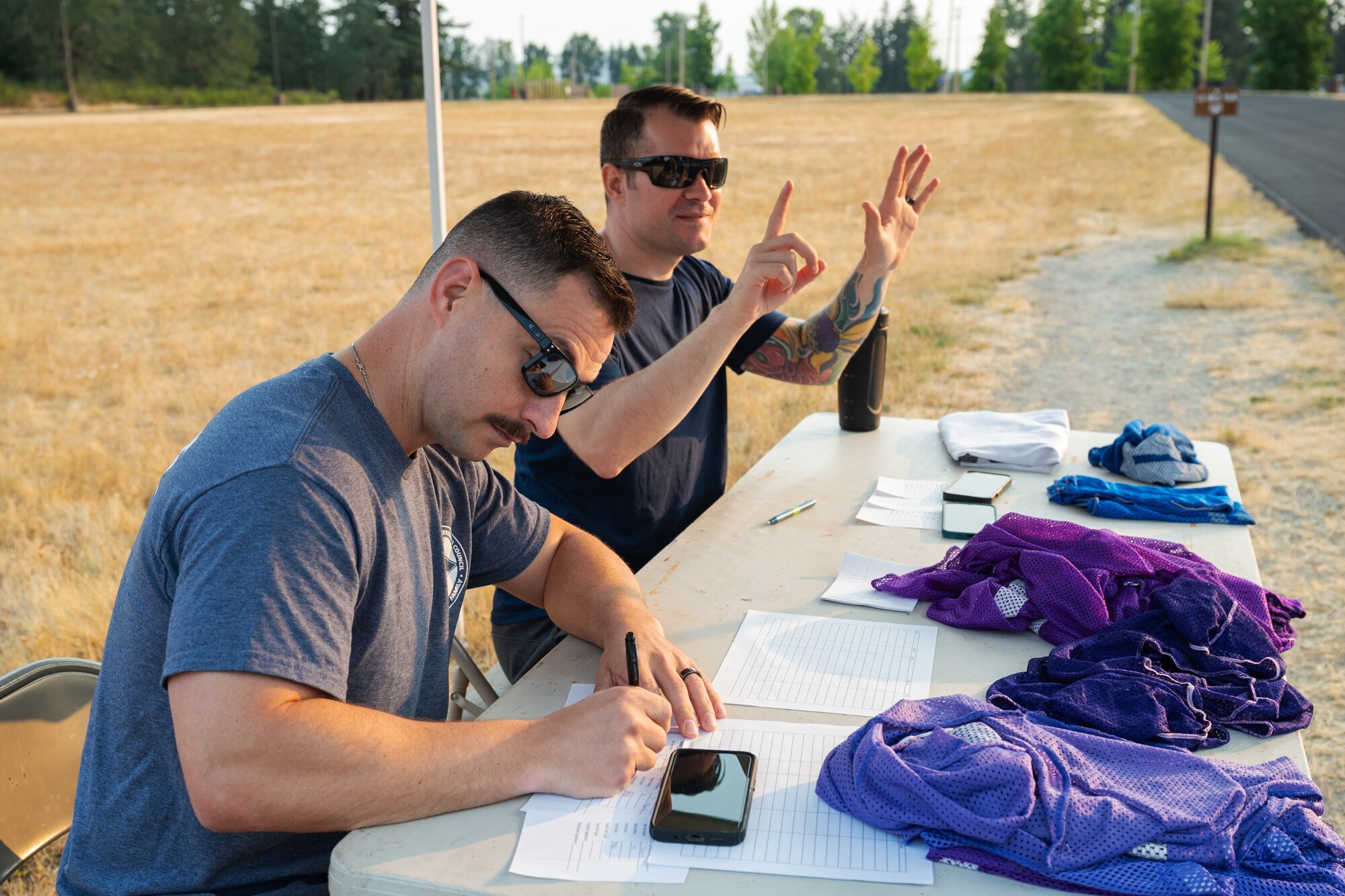 U.S. Air Force Master Sgt. David Woliver, 62d Maintenance Squadron assistant first sergeant, left, and Tech. Sgt. Steven Brooks, 62d Aircraft Maintenance Squadron assistant first sergeant, count laps for Dash for Danielle Memorial Run participants at Joint Base Lewis-McChord, Washington, Aug. 9, 2024.