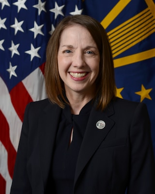 A woman poses for a photo in front of two flags.