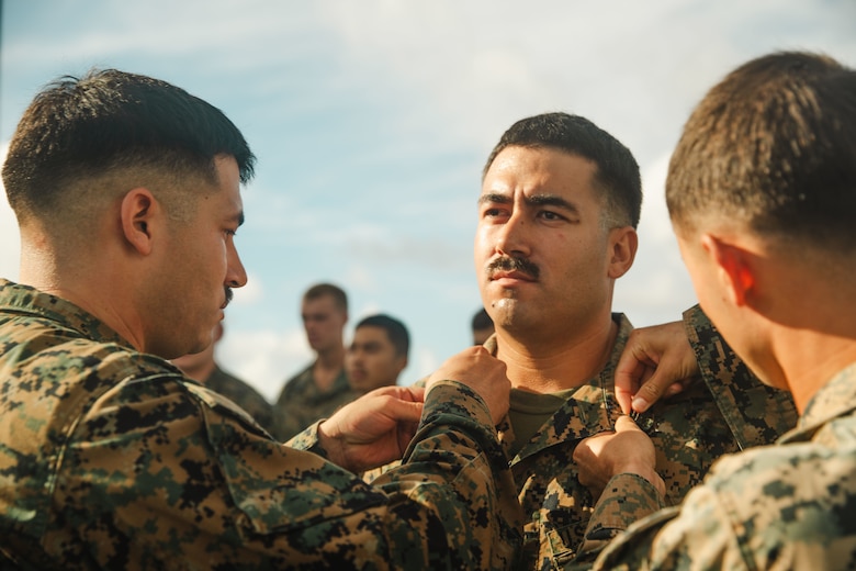 U.S. Marine Corps Sgt. Albert Morelli, center, an assistant patrol leader assigned to Bravo Company, Battalion Landing Team 1/5, 15th Marine Expeditionary Unit, is promoted to the rank of sergeant by his brother Gunnery Sgt. Joseph Morelli, left, the communications maintenance chief assigned to the 15th MEU, aboard the amphibious assault ship USS Boxer (LHD 4) in the Pacific Ocean Aug. 1, 2024.