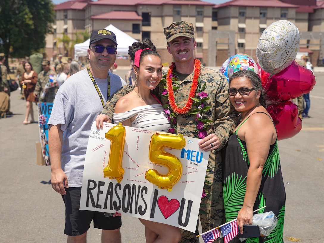 U.S. Marine Corps Cpl. Aidan Hekker, a combat photographer assigned to the 15th Marine Expeditionary Unit, and a native of South Carolina, poses for a photo with his wife and family at a welcome home reception at Marine Corps Base Camp Pendleton, California Aug. 10, 2024. Elements of the 15th MEU, embarked aboard amphibious transport dock USS Somerset (LPD 25), returned to Marine Corps Base Camp Pendleton after a seven-month deployment to the Indo-Pacific region in support of regional stability and a free and open Indo-Pacific. (U.S. Marine Corps photo by 1st Lt. Robert Nanna)