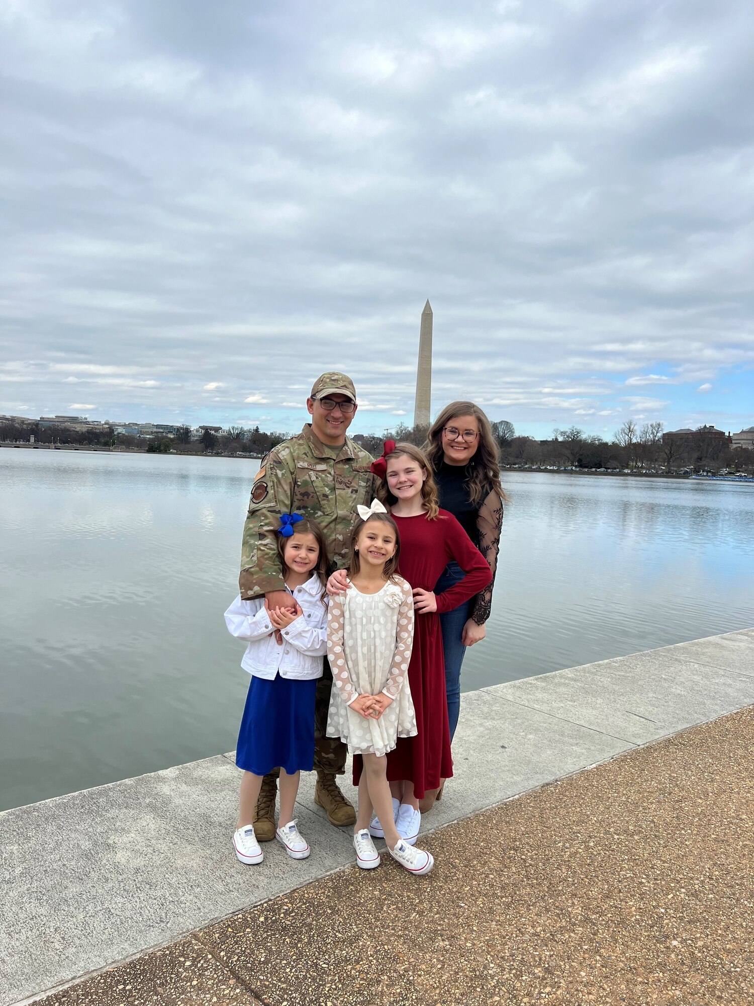 A family poses for a group photo with the Washington Monument behind them.