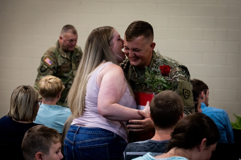 Sgt. 1st Class Robert Moll, an engineer with the 613th Engineer Facilities Detachment, 149th Maneuver Enhancement Brigade, gives a bouquet of flowers to his wife at the Springfield Army National Guard Armory in Springfield, Kentucky on August 5, 2024. Approximately 15 Soldiers of the 613 FACDET are departing for Kuwait for base directorate of public works mission at Camp Buehring. (U.S. Army National Guard photo by Andy Dickson)