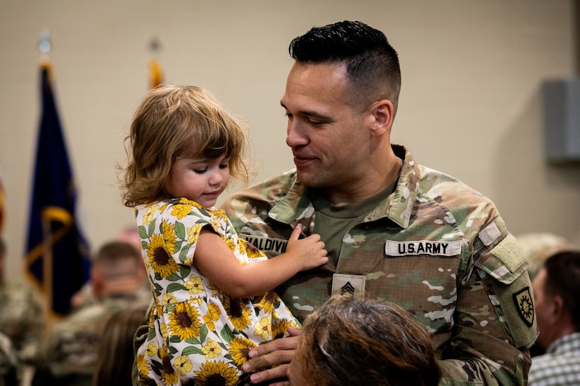 Sgt. 1st Class Cory Valdivieso, an engieer with the 613th Engineer Facilities Detachment, 149th Maneuver Enhancement Brigade, hugs his family at the Springfield Army National Guard Armory in Springfield, Kentucky on August 5, 2024. Approximately 15 Soldiers of the 613 FACDET are departing for Kuwait for base directorate of public works mission at Camp Buehring. (U.S. Army National Guard photo by Andy Dickson)