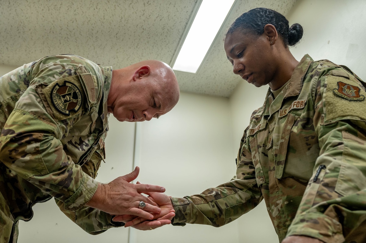 A physical therapist demonstrates treatment techniques for a service member.