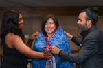 240803-N-AA383-1389 SEATTLE (Aug. 4, 2024) Command Master Chief Katrina R. Lockett and Roberto de Jesus Navarro place a quilt from American Hero Quilts on Information Systems Technician 2nd Class Nancy J. Cruz Gonzalez during the Returning Warrior Workshop (RWW) hosted by Navy Reserve Region Readiness and Mobilization Command (REDCOM) Everett. RWWs, a component of the Yellow Ribbon Program, provide an opportunity for Reserve Component (RC) Sailors who have recently returned from a deployment, mobilization or individual augmentation to address reintegration challenges, offering a chance to relax, reconnect and rebuild relationships. (U.S. Navy photo by Mass Communication Specialist 1st Class Yudy A. Palacios)