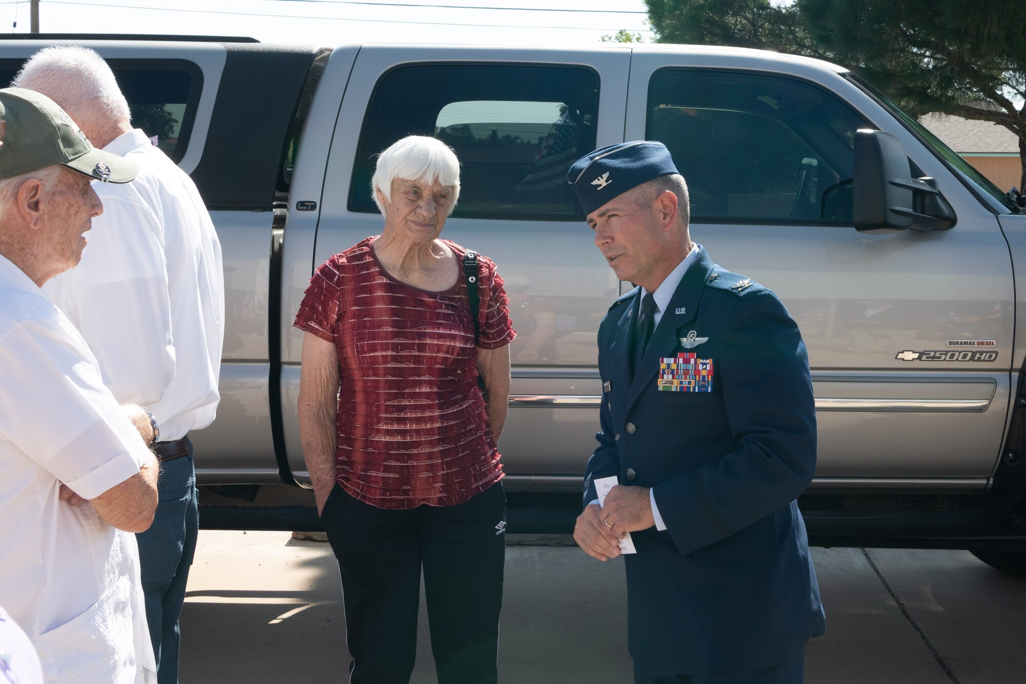 A man in military dress uniform speaks to several elderly people.