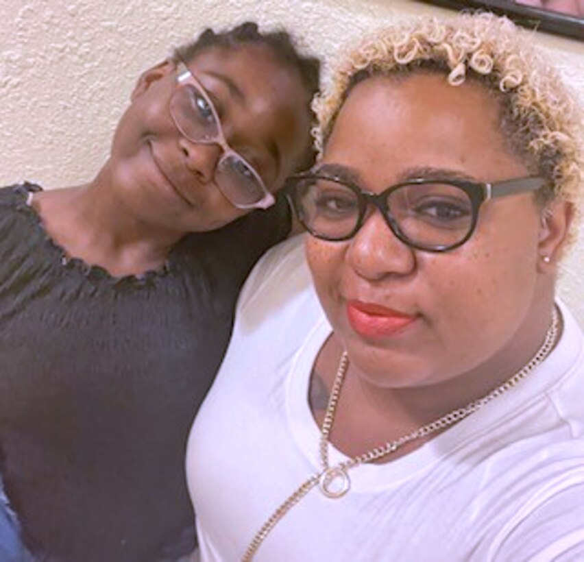 A young girl and her mom pose for the camera. both are looking into the camera.