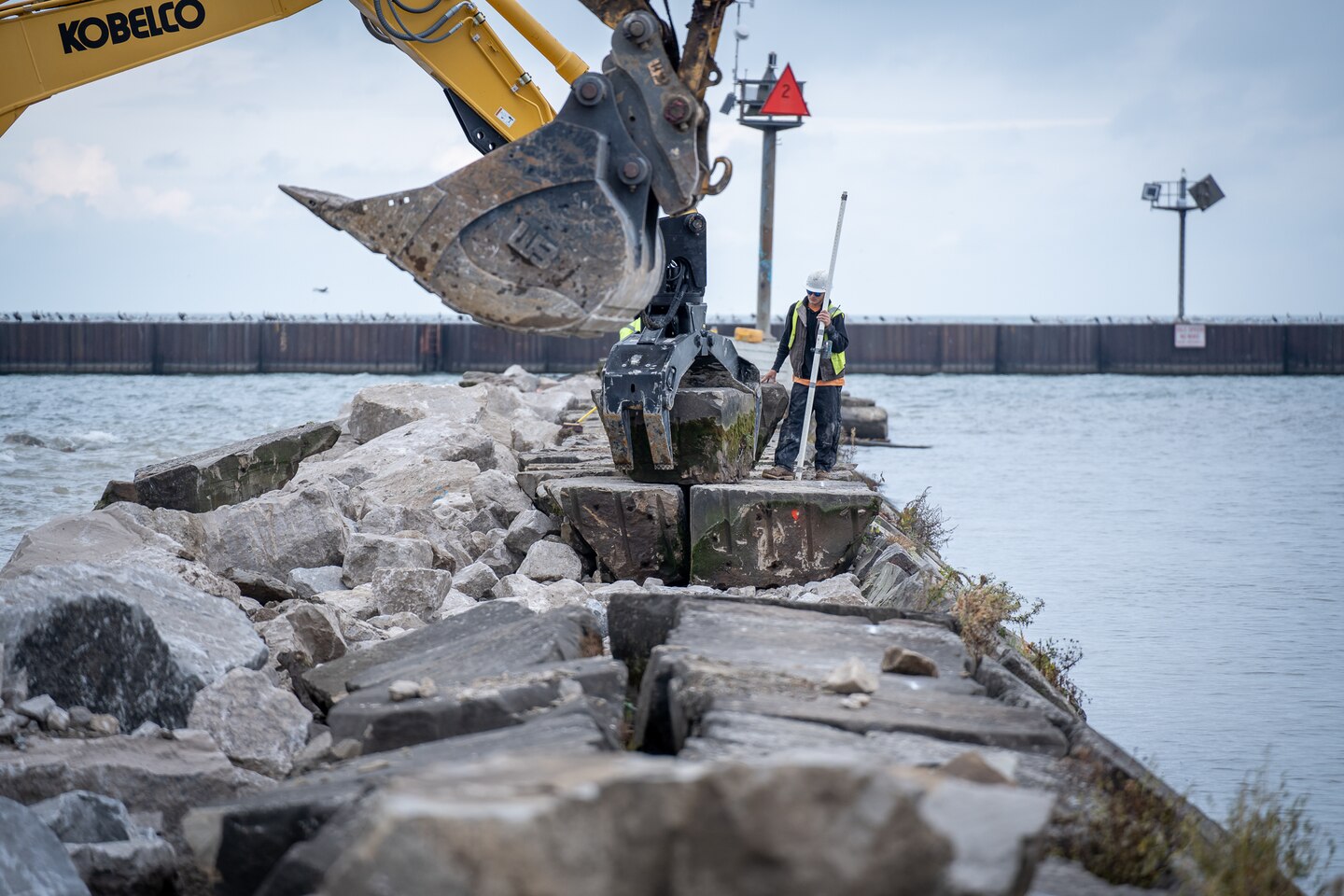 Construction equipment places large stones on a pier between Lake Erie and the Vermilion River in Ohio