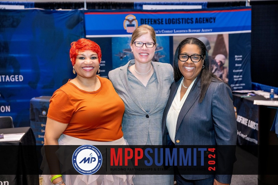 Three women - two black, one white - stand shoulder to shoulder facing the camera.