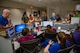 Doctors and nurses in various colors of hospital uniforms are standing and sitting around a nurses' station in an animal hospital discussing something.