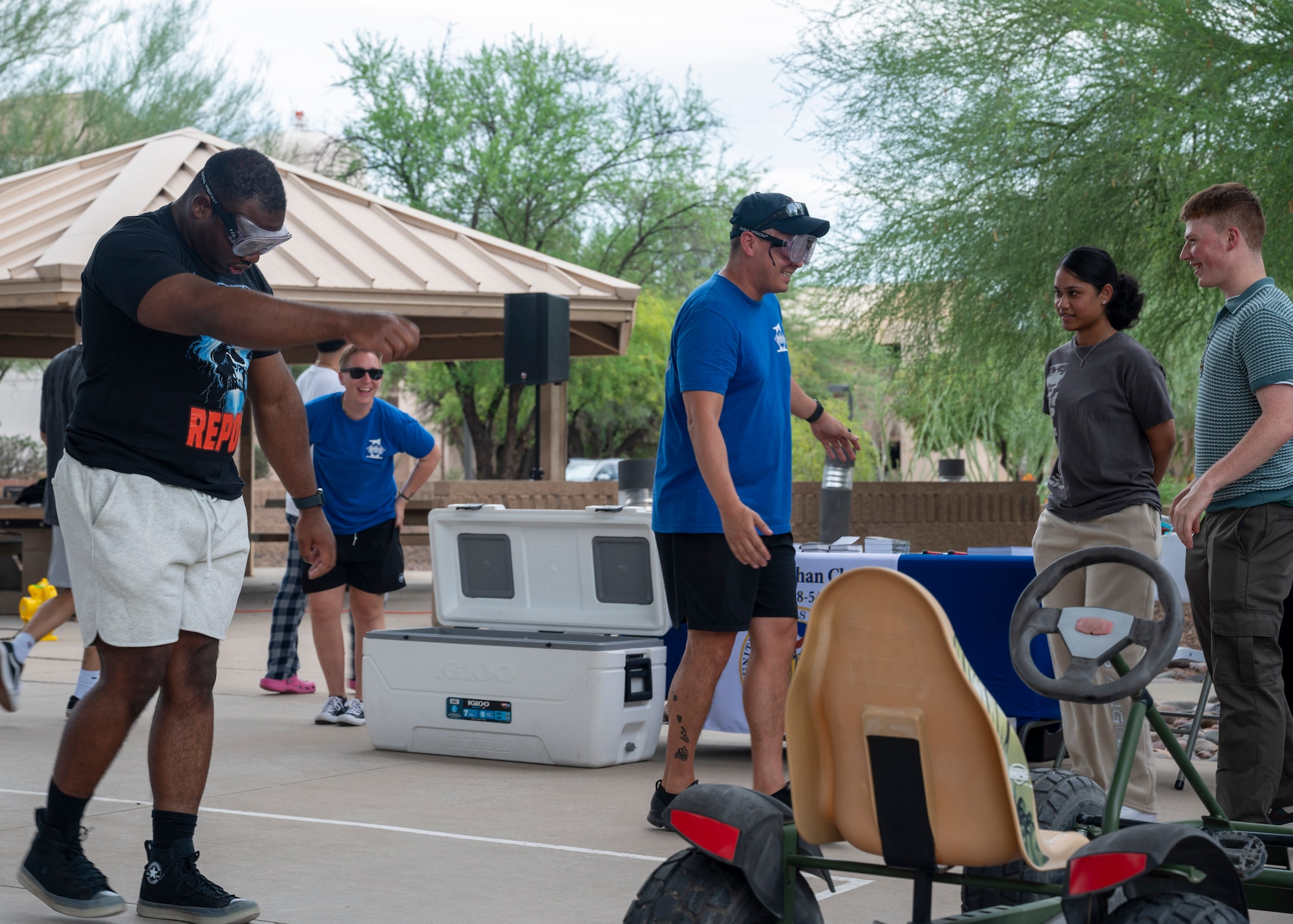 U.S. Airmen walk while wearing goggles that simulate drunkenness during the Summer Dorm Bash at Davis-Monthan Air Force Base, Ariz., Aug. 9, 2024. The Alcohol and Drug Abuse Prevention and Treatment Program provided the goggles to educate Airmen on the effects alcohol can have on them. (U.S. Air Force photo by Airman 1st Class William Finn V)