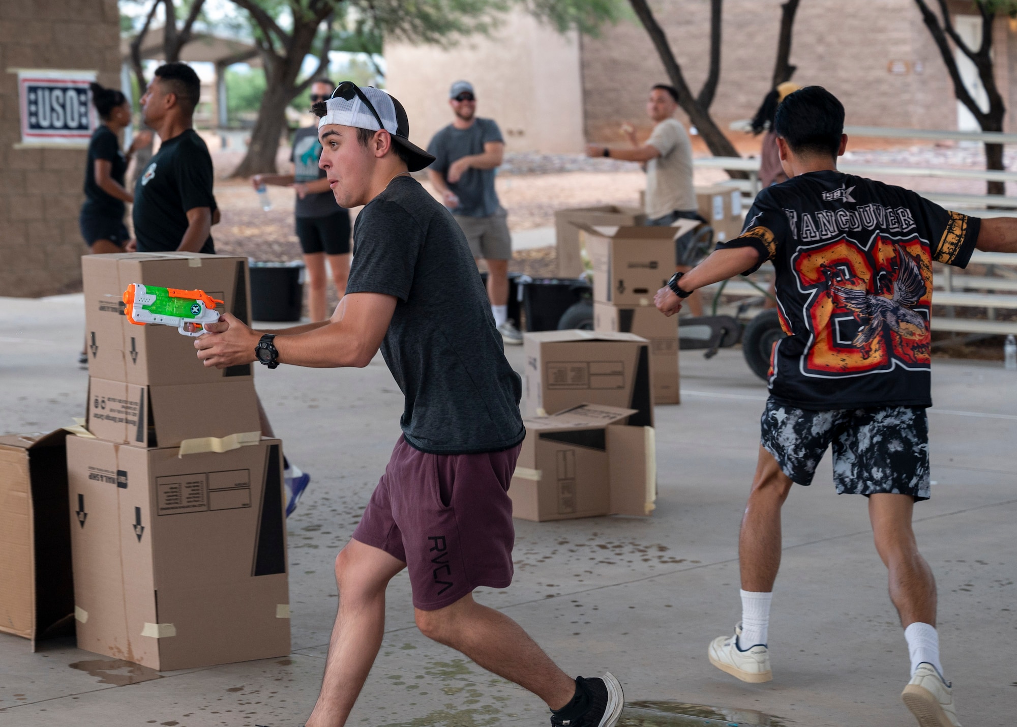 U.S. Airmen have a water gun fight during the Summer Dorm Bash at Davis-Monthan Air Force Base, Ariz., Aug. 9, 2024. The Dorm Bash hosted several booths and games for airmen to participate in and connect with one another. (U.S. Air Force photo by Airman 1st Class William Finn V)