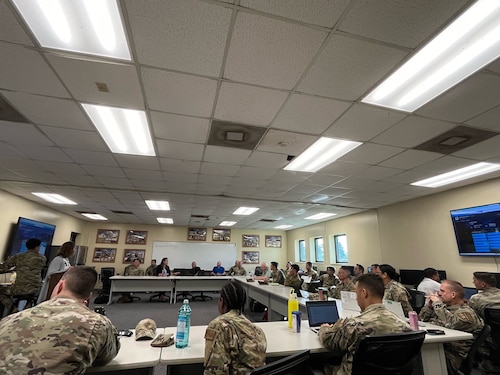 Members from the 12th Air Task Force A-Staff listen intently while sitting at a table