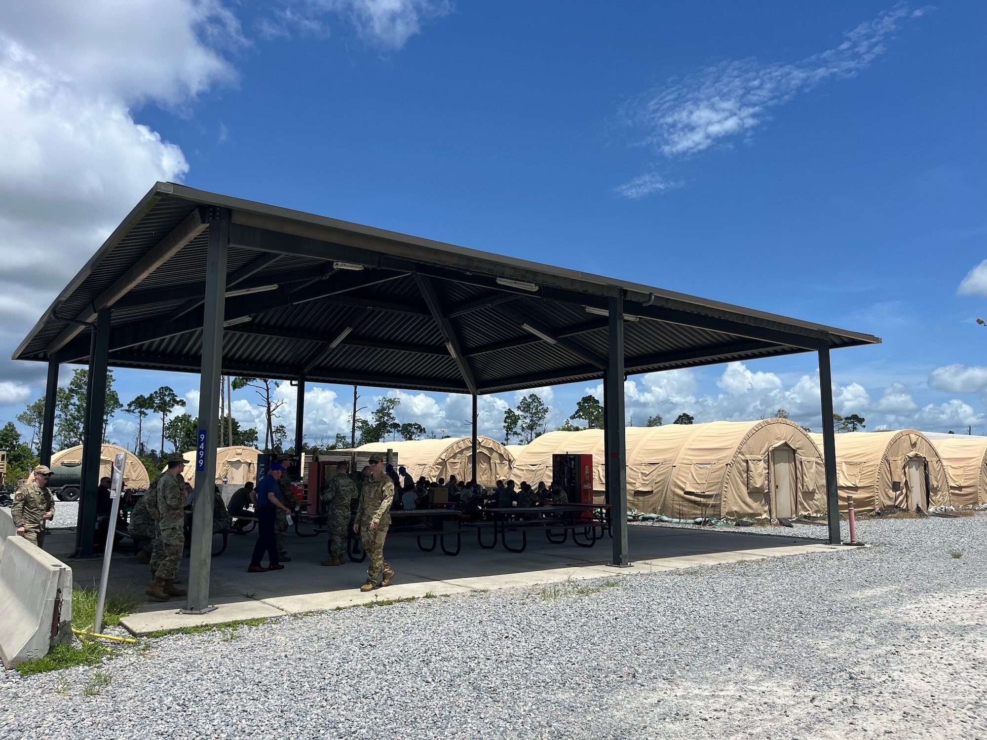 Members from the 12th Air Task Force A-Staff sit under an outdoors gazebo surrounded by tents