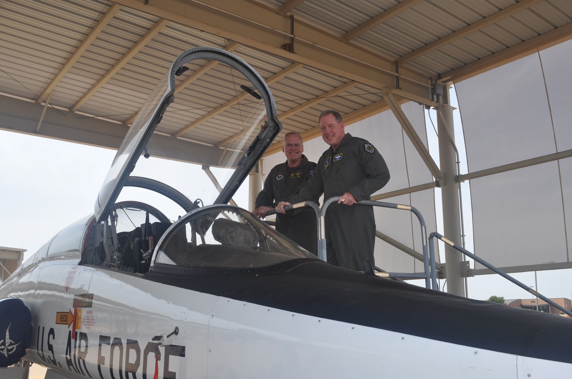 Two men stand next to an airplane.