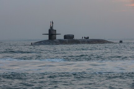 A submarine sails in open water at twilight.