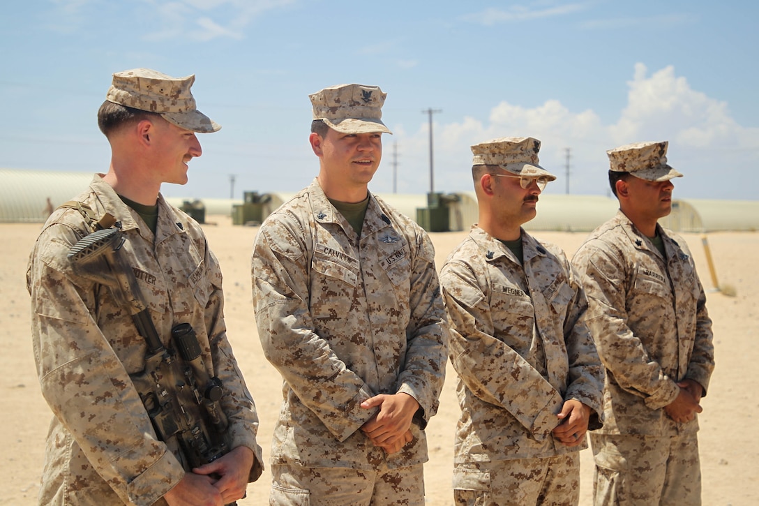 A U.S. Marine and Sailors with 1st Battalion, 2d Marine Regiment, 2d Marine Division, stand-by to be awarded a Navy and Marine Corps Commendation Medal on Marine Corps Air-Ground Combat Center, Twentynine Palms, California, Aug. 11, 2024. Servicemembers were awarded for rendering aid to a Marine during a live fire exercise, ultimately saving his life. (U.S. Marine Corps photo by Lance Cpl. Weston Lindstrom)