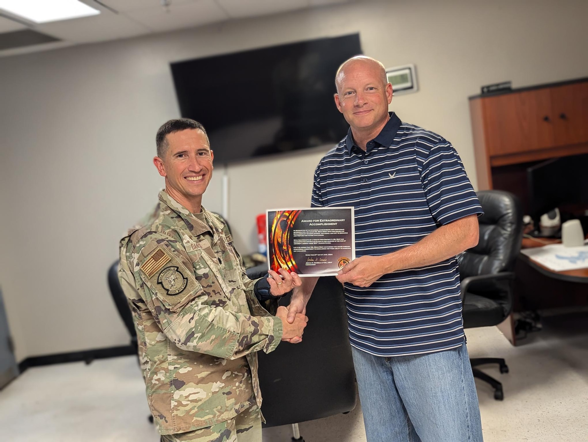 A man in uniform presents another man a certificate.